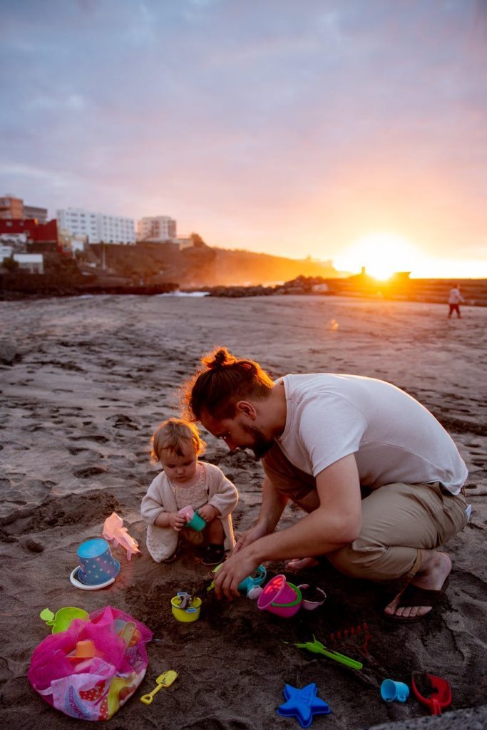 father and child playing on sand