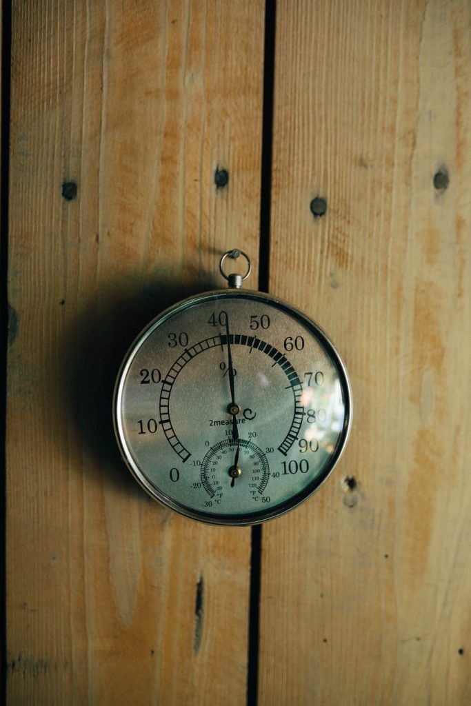 hanging round thermometer on wooden wall