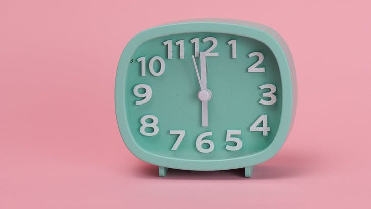 a green analog clock on pink background