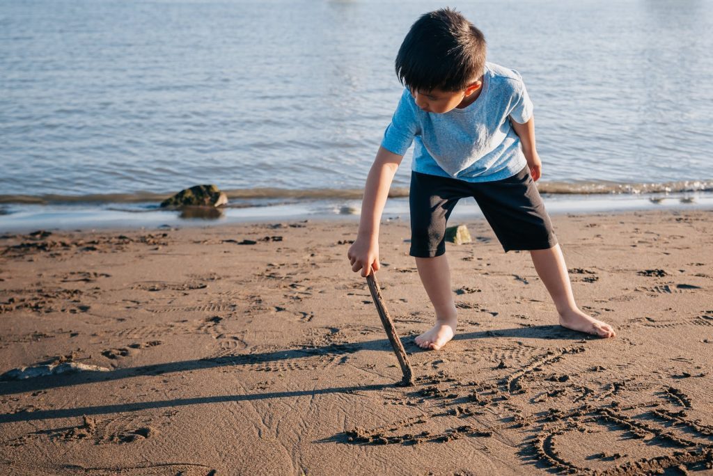 young boy drawing on sand